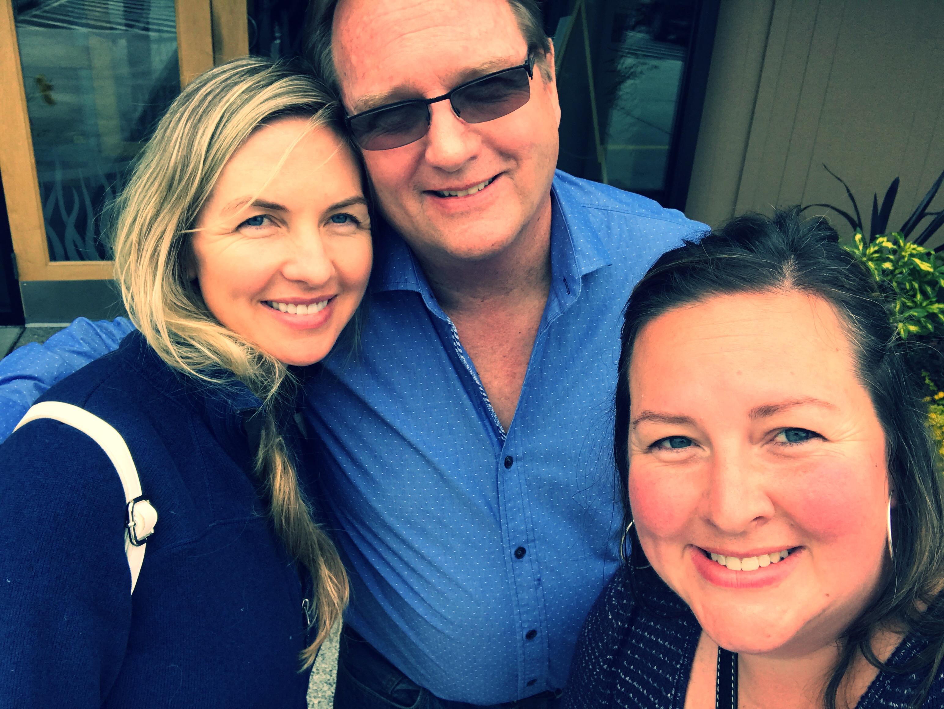 Three friends happily pose for a photo while enjoying a cheerful moment outdoors.