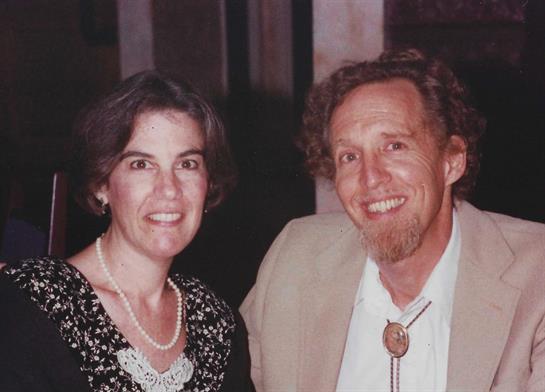 Two people share smiles while seated at a restaurant, dressed elegantly for the evening.