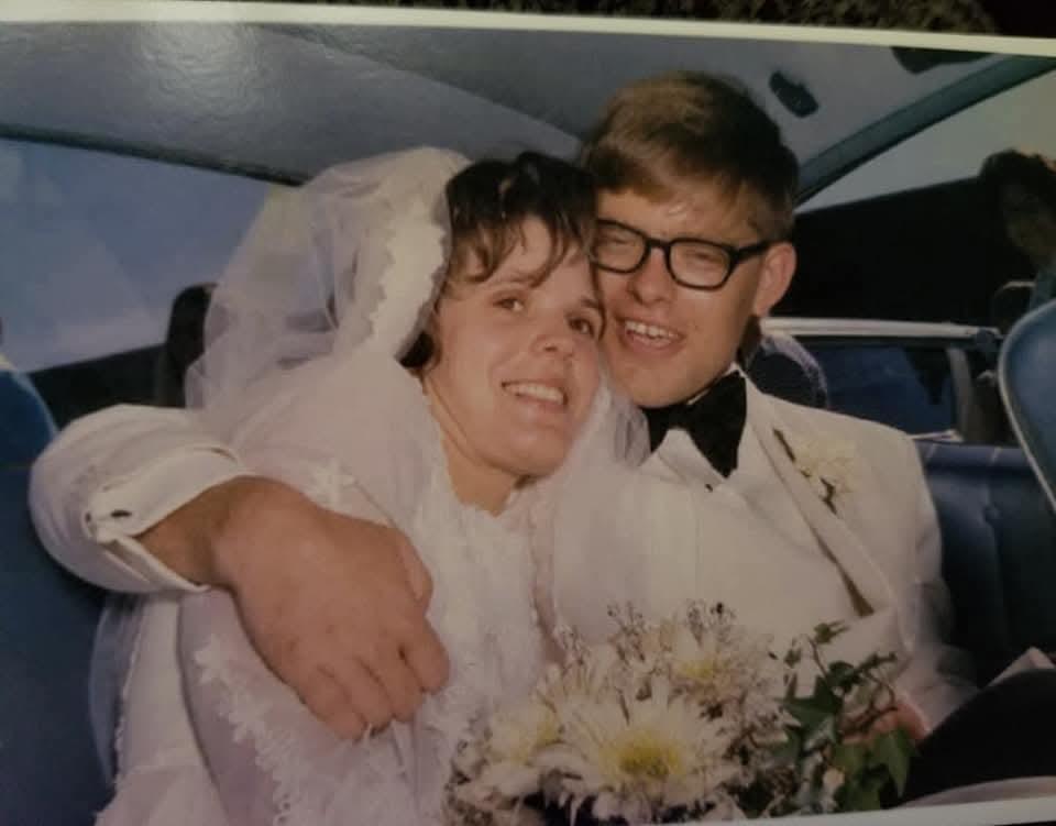 A couple joyfully embraces inside a vintage car immediately after their wedding ceremony.
