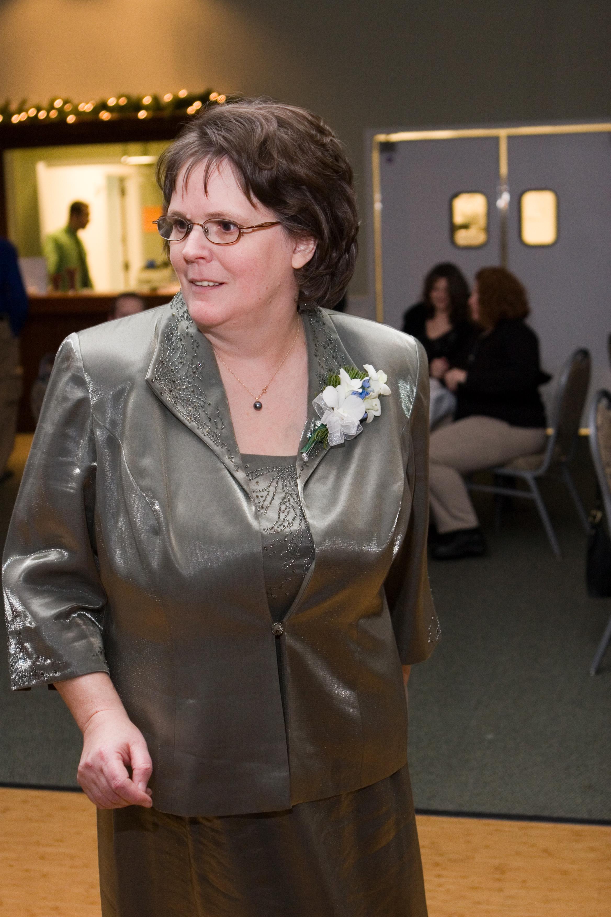 A woman in a stylish silver outfit enjoys dancing during a lively celebration with guests.