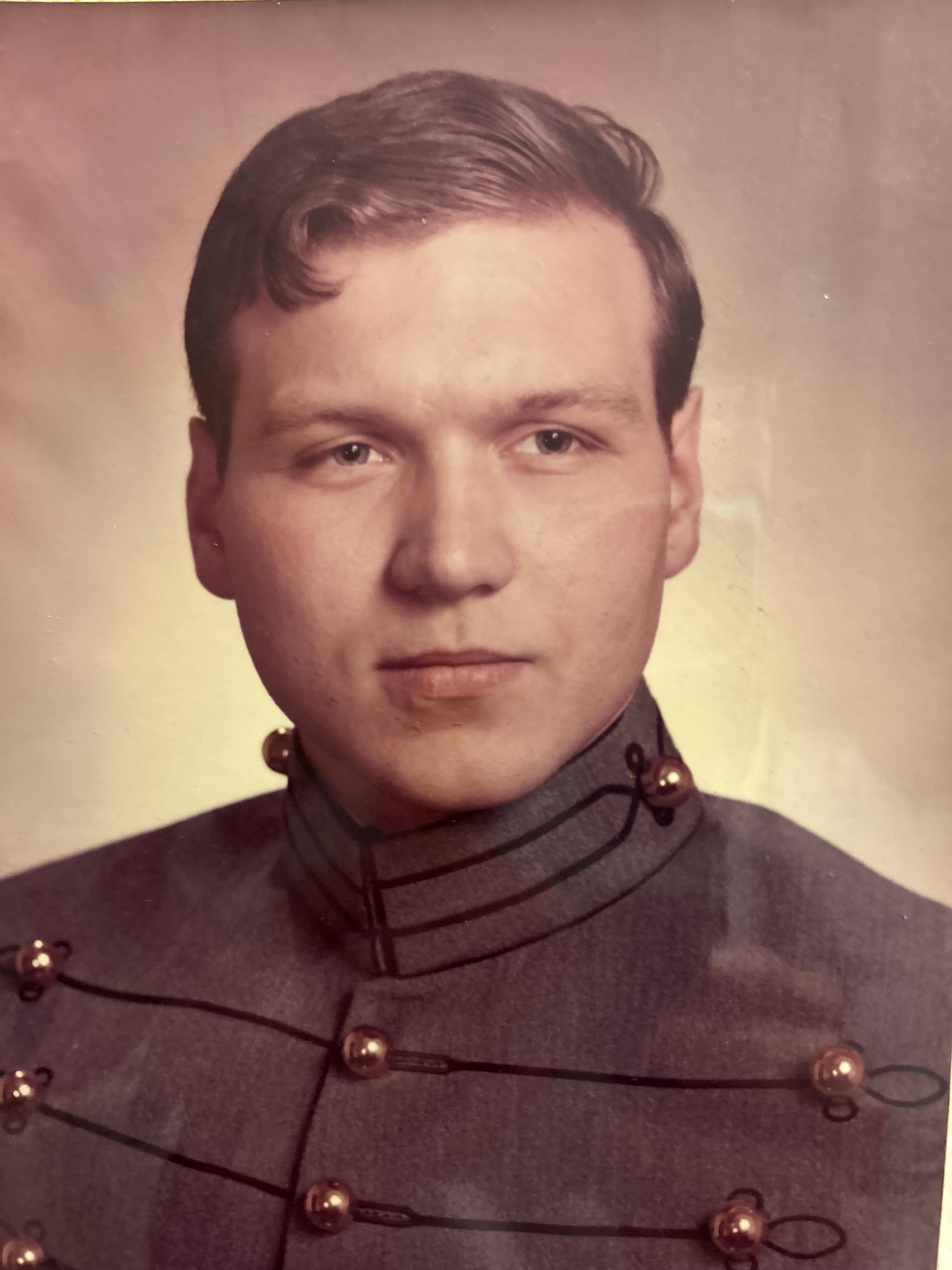A young man wears a vintage military uniform, showcasing intricate details and buttons while posing.