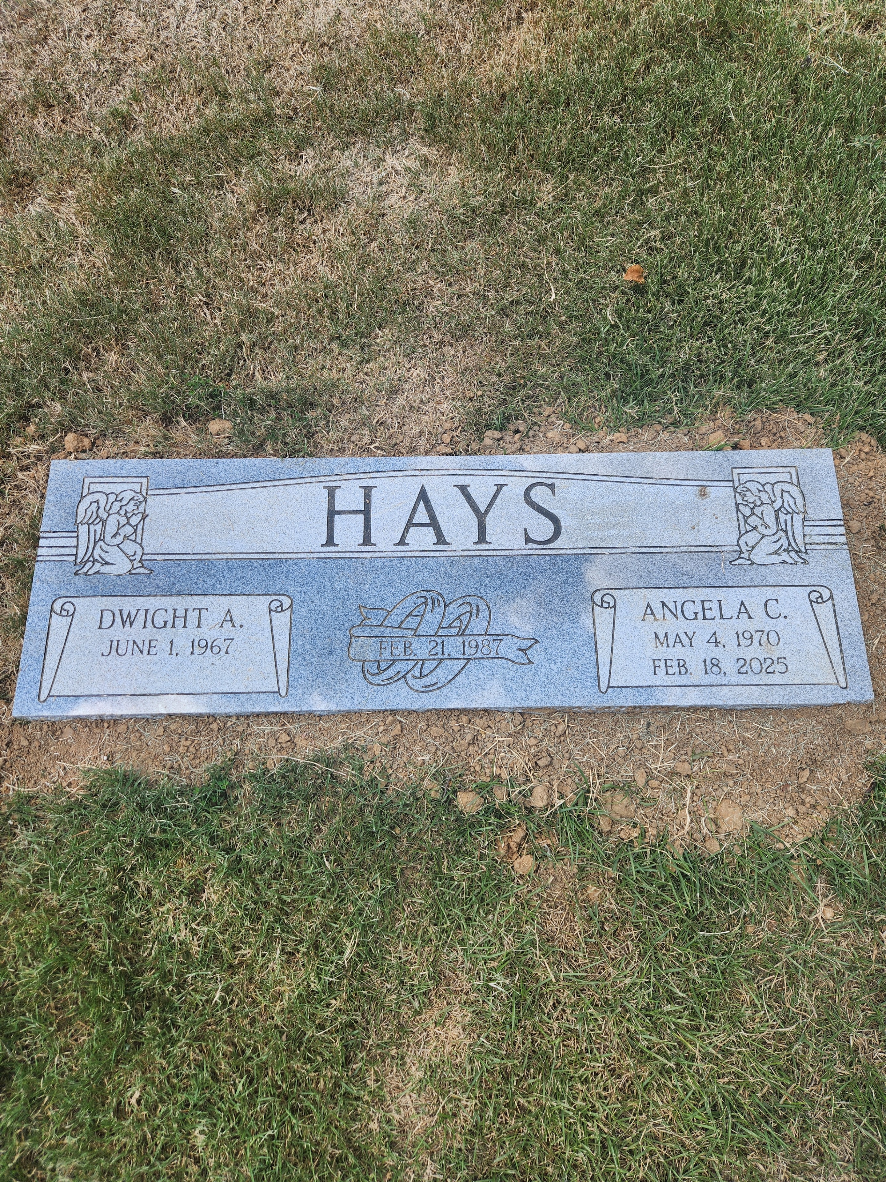 The engraved memorial plaque honors Dwight A. and Angela C. Hays in a tranquil cemetery.