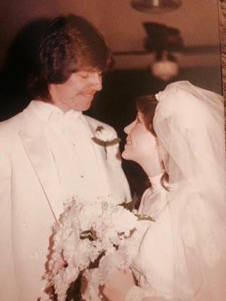 A couple gazes into each other's eyes during their wedding ceremony, surrounded by flowers.