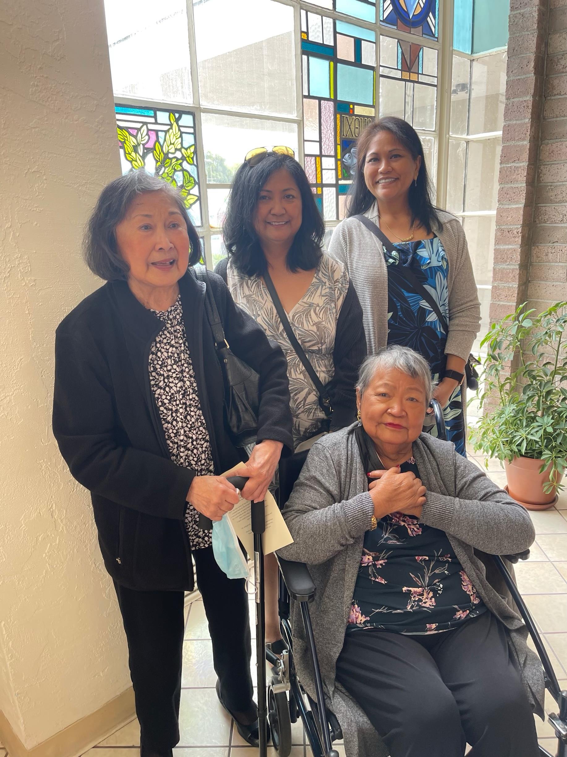 Four women gather inside a community center, enjoying each other's company and conversation.