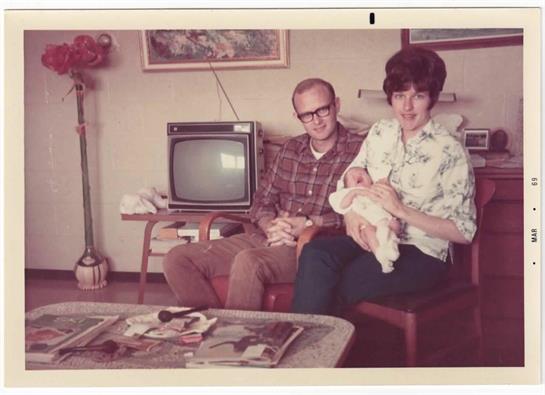 A man and woman sitting on a chair holding a cat