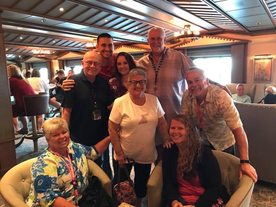 A group of friends smiles and poses together at a restaurant, enjoying their time together.