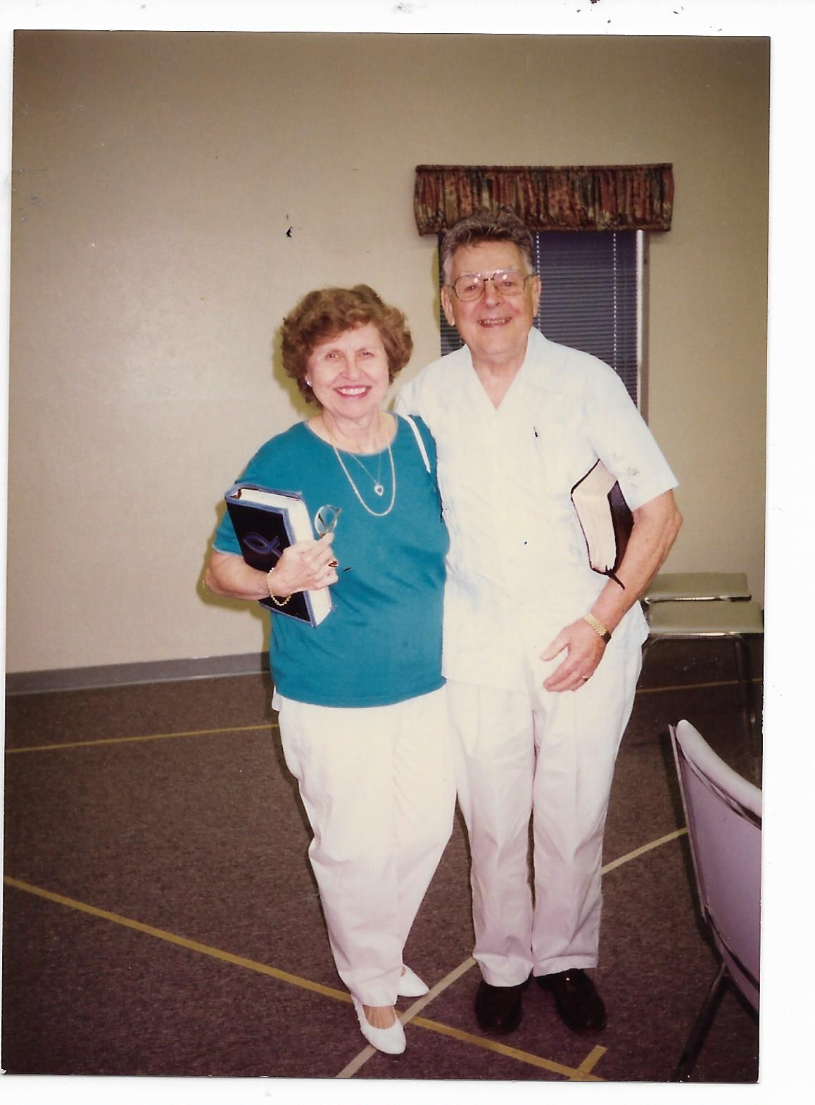 Two senior individuals share a joyful moment during a community event in a welcoming space.