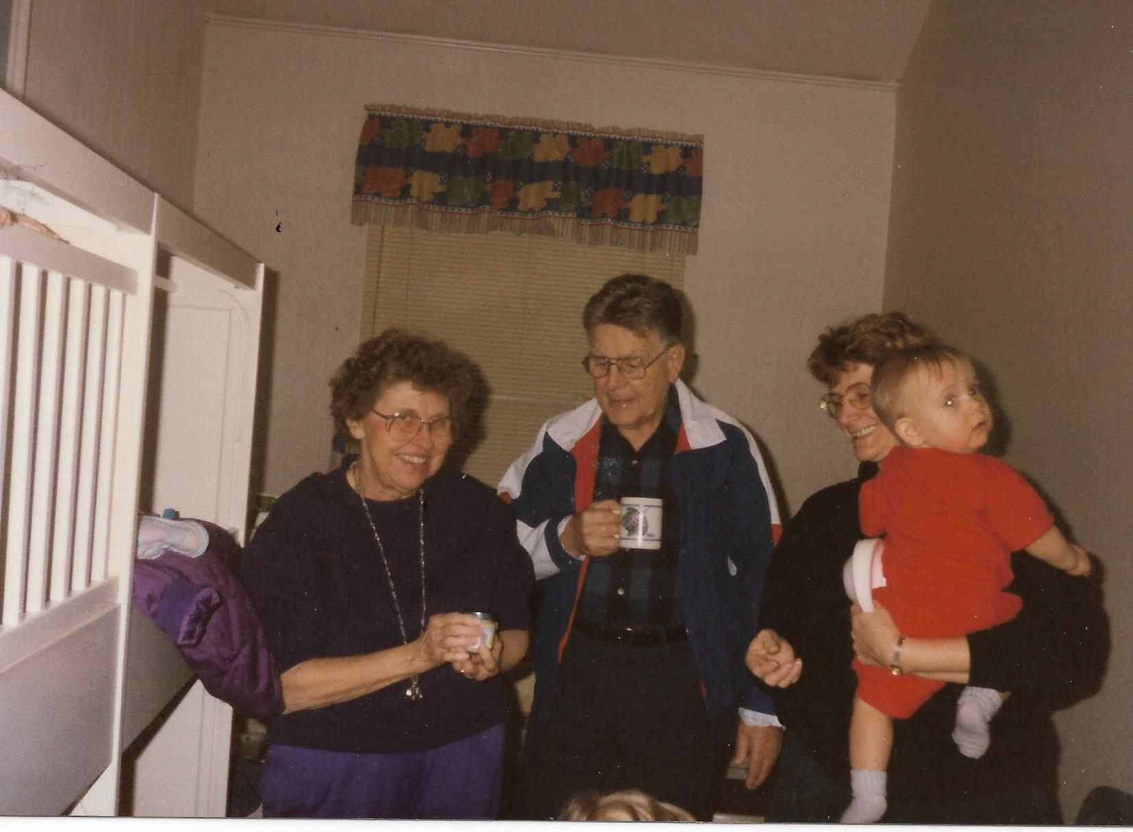 Four family members share laughter and stories in a cozy, warmly lit room.