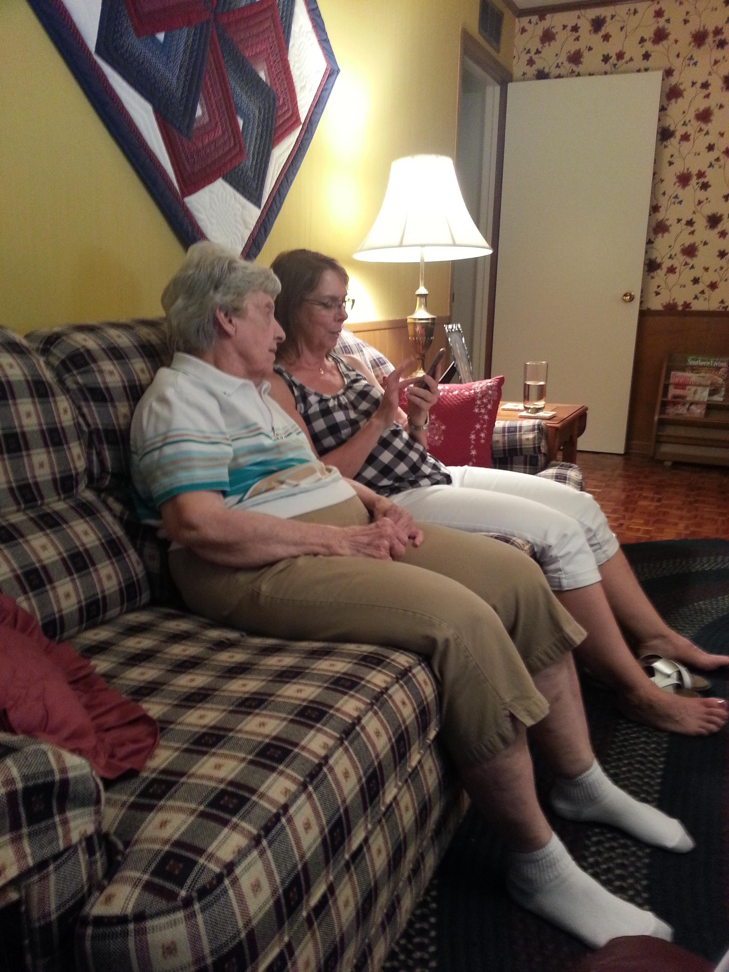 Two women sit comfortably on a couch, enjoying each other's company during a home gathering.