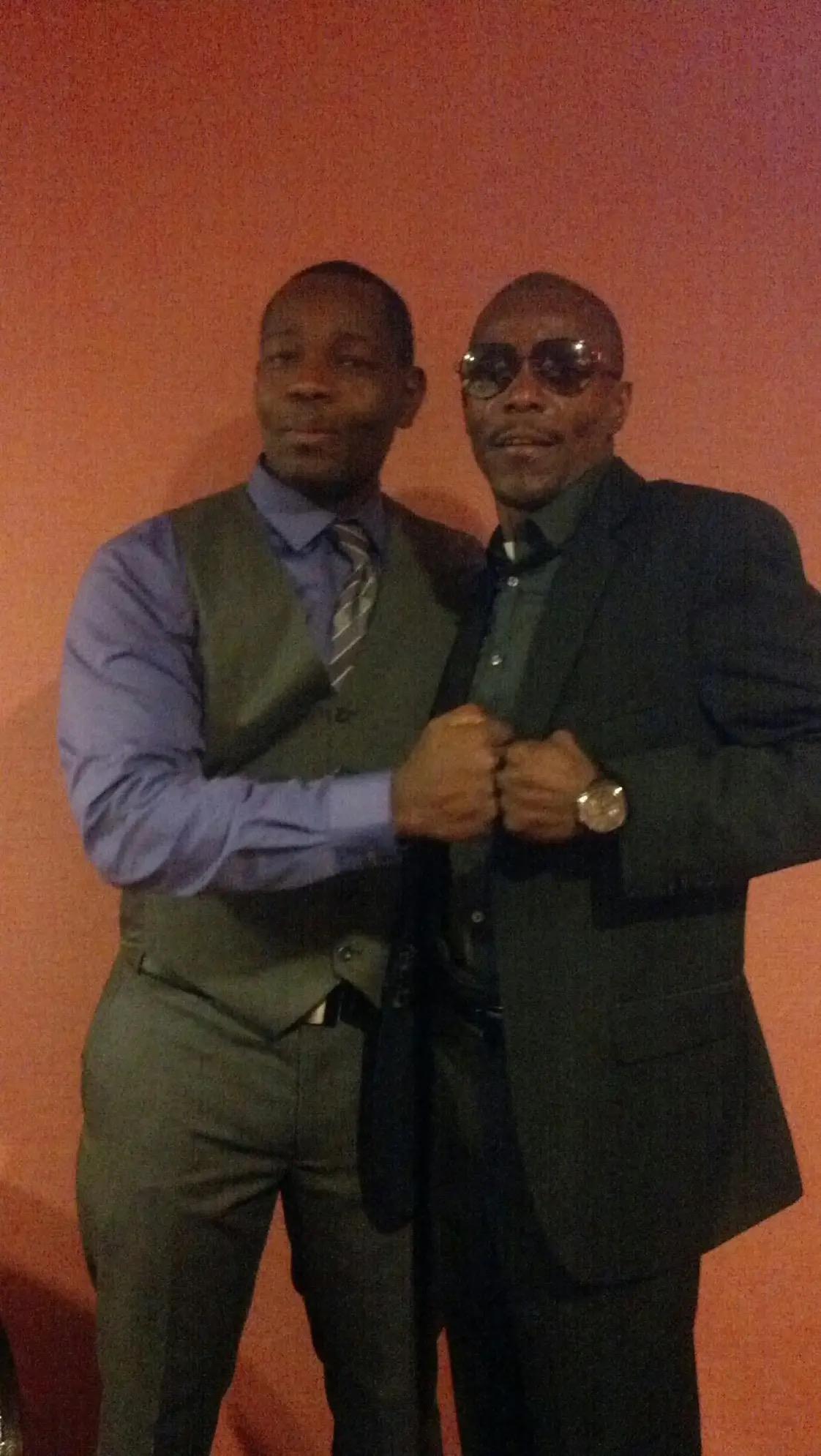 Men are smiling and shaking hands while dressed formally, celebrating a special occasion.