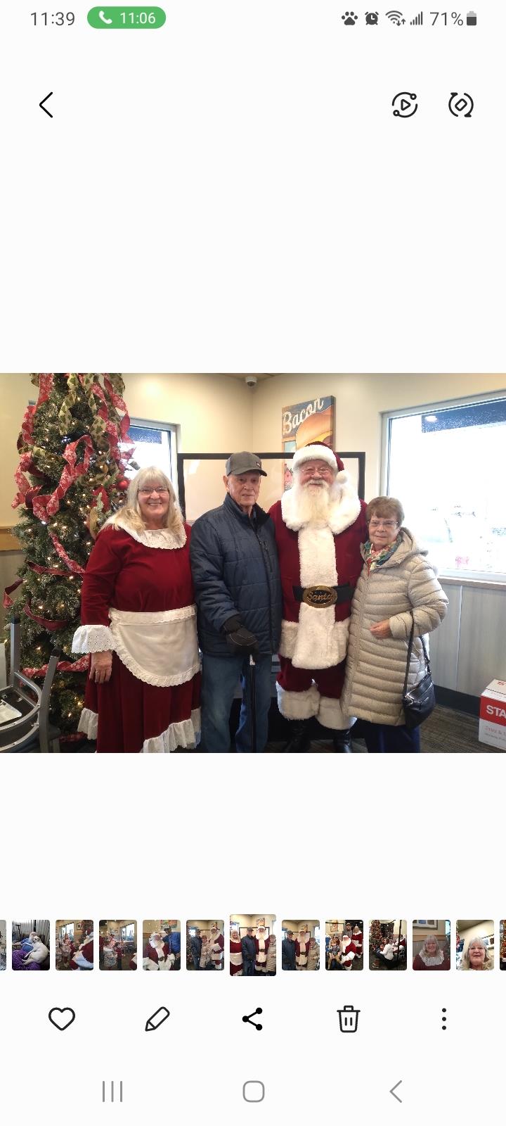 Families gather joyfully around Santa and Mrs. Claus for a festive holiday celebration.