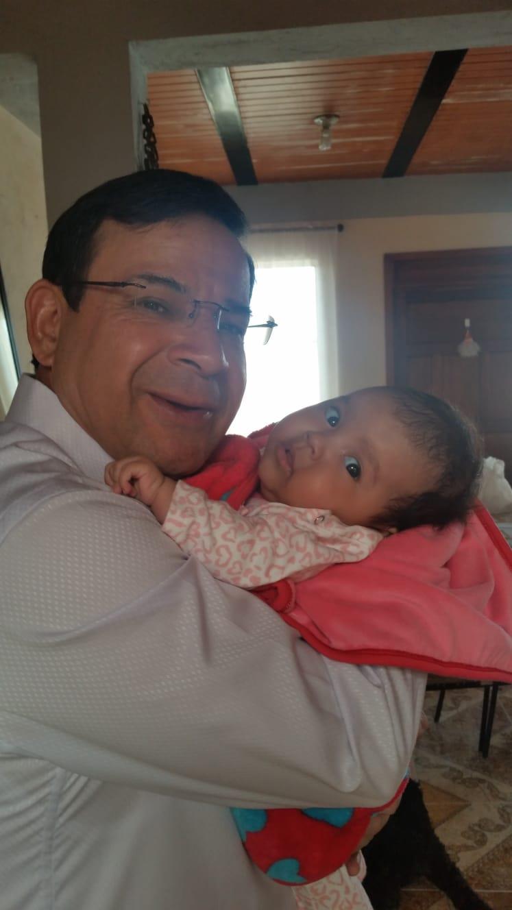 A man lovingly cradles a baby in a cozy indoor space while smiling warmly at the child.