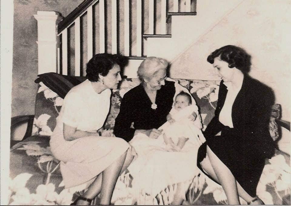 Women engage in lively conversation while seated with a baby in a charming home.