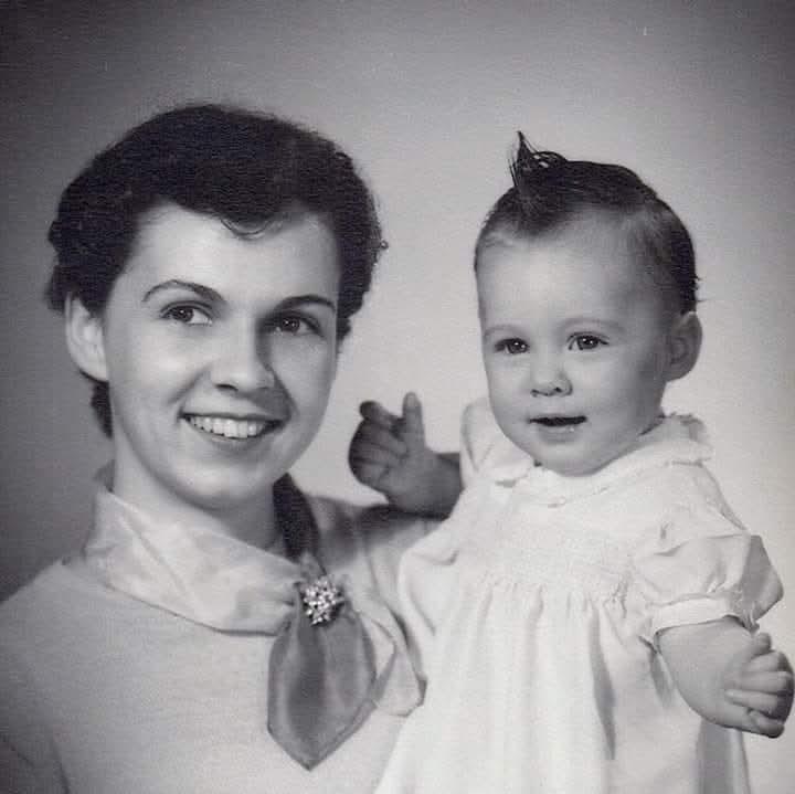 A woman joyfully holds a baby in her arms, both smiling warmly, capturing a loving bond.
