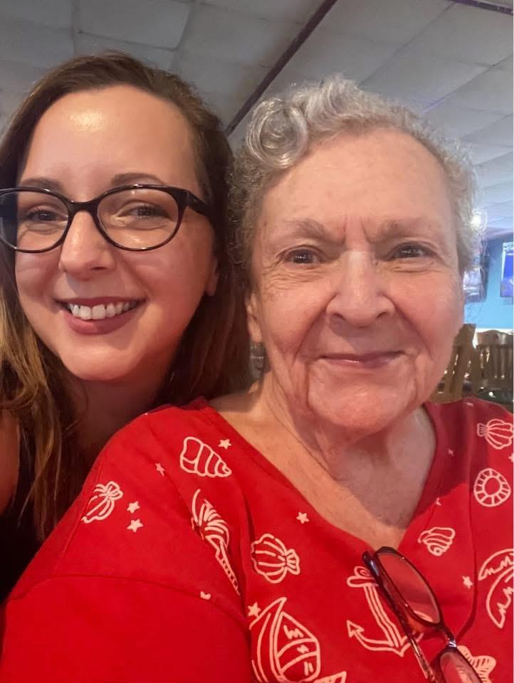 Women sit close together, smiling warmly in a lively setting filled with good vibes.