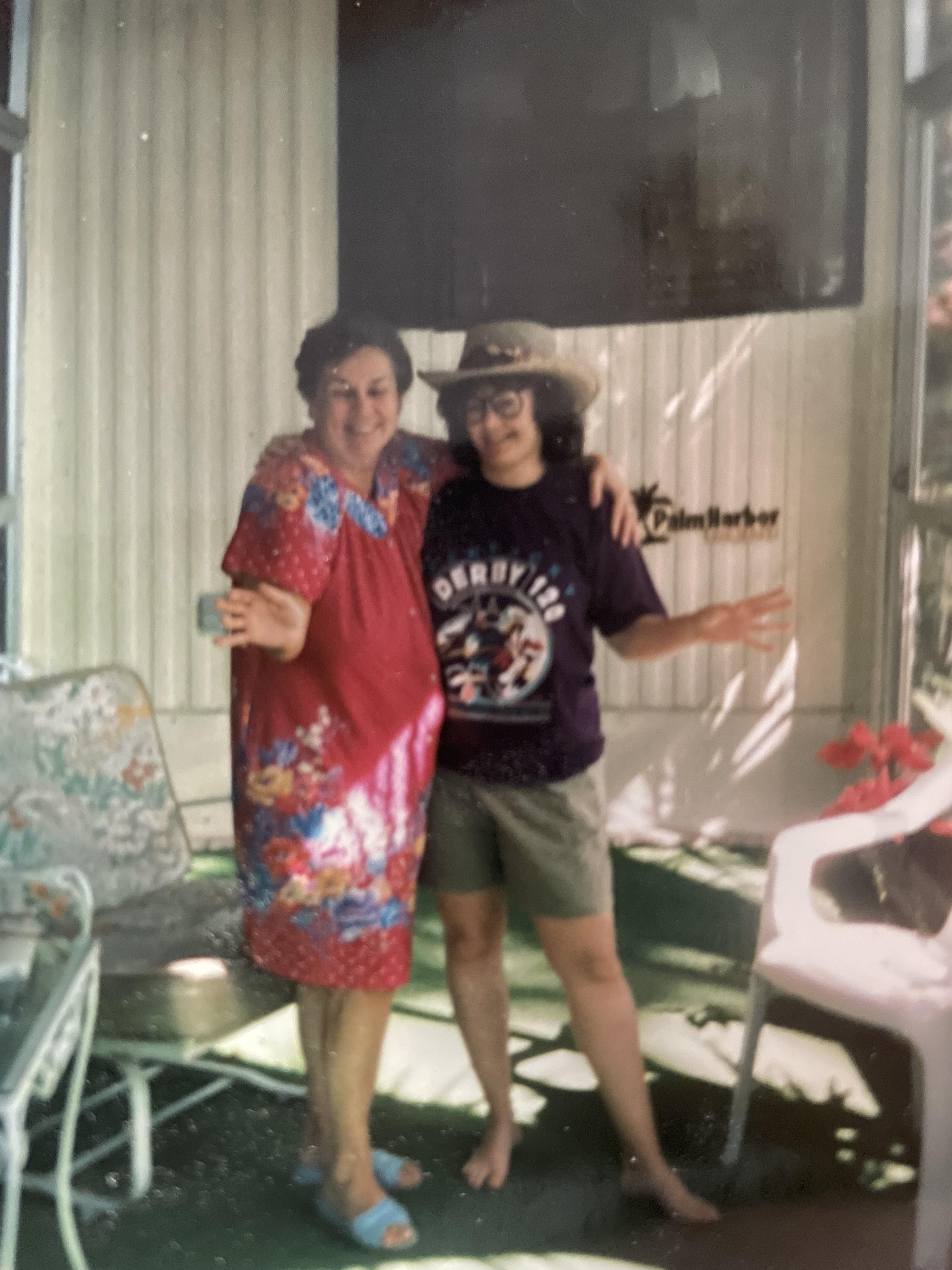 Two friends happily pose together in a warm, inviting outdoor space filled with sunlight.