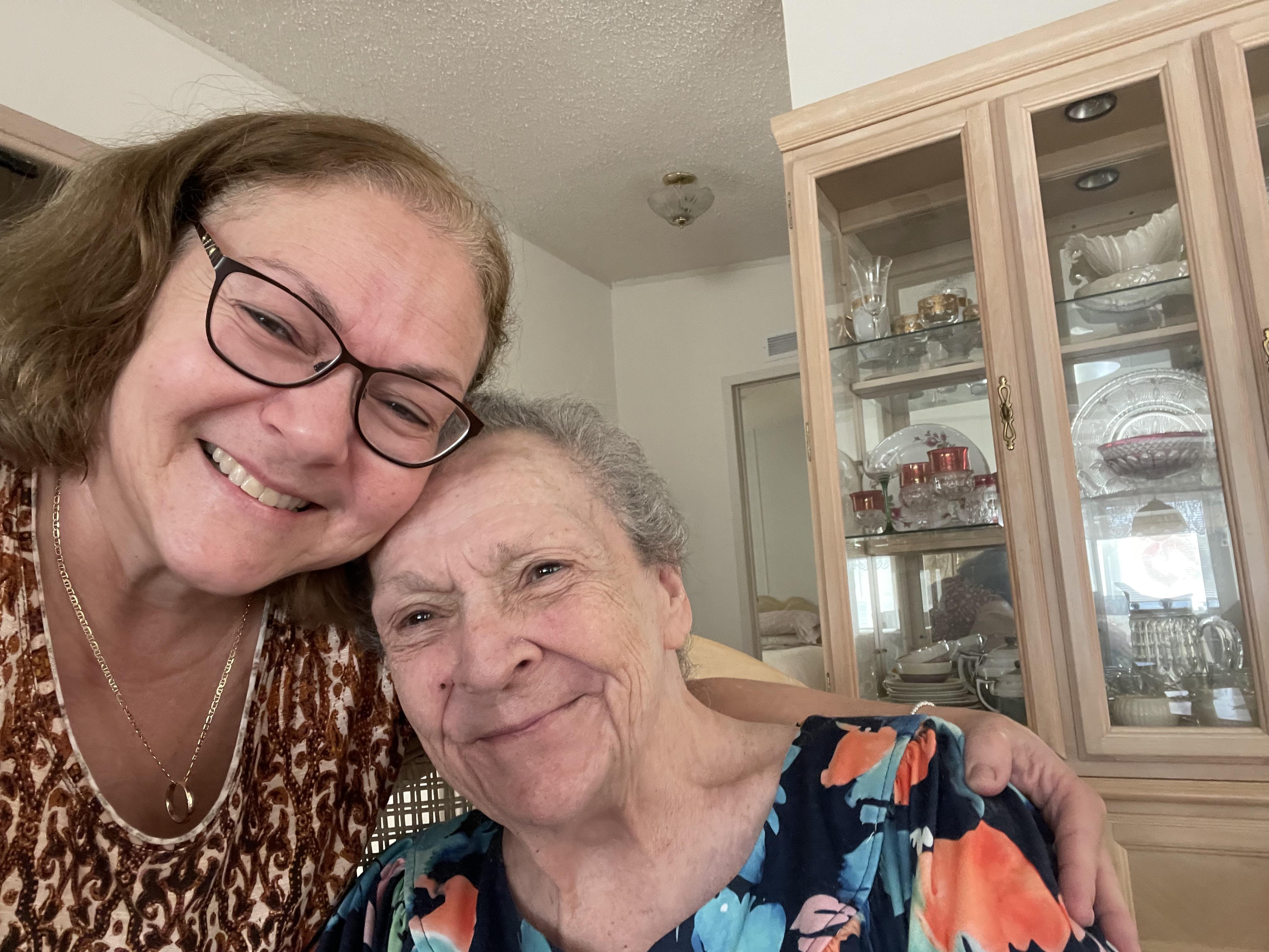 Two women share a joyful smile together in a welcoming living room filled with memories.