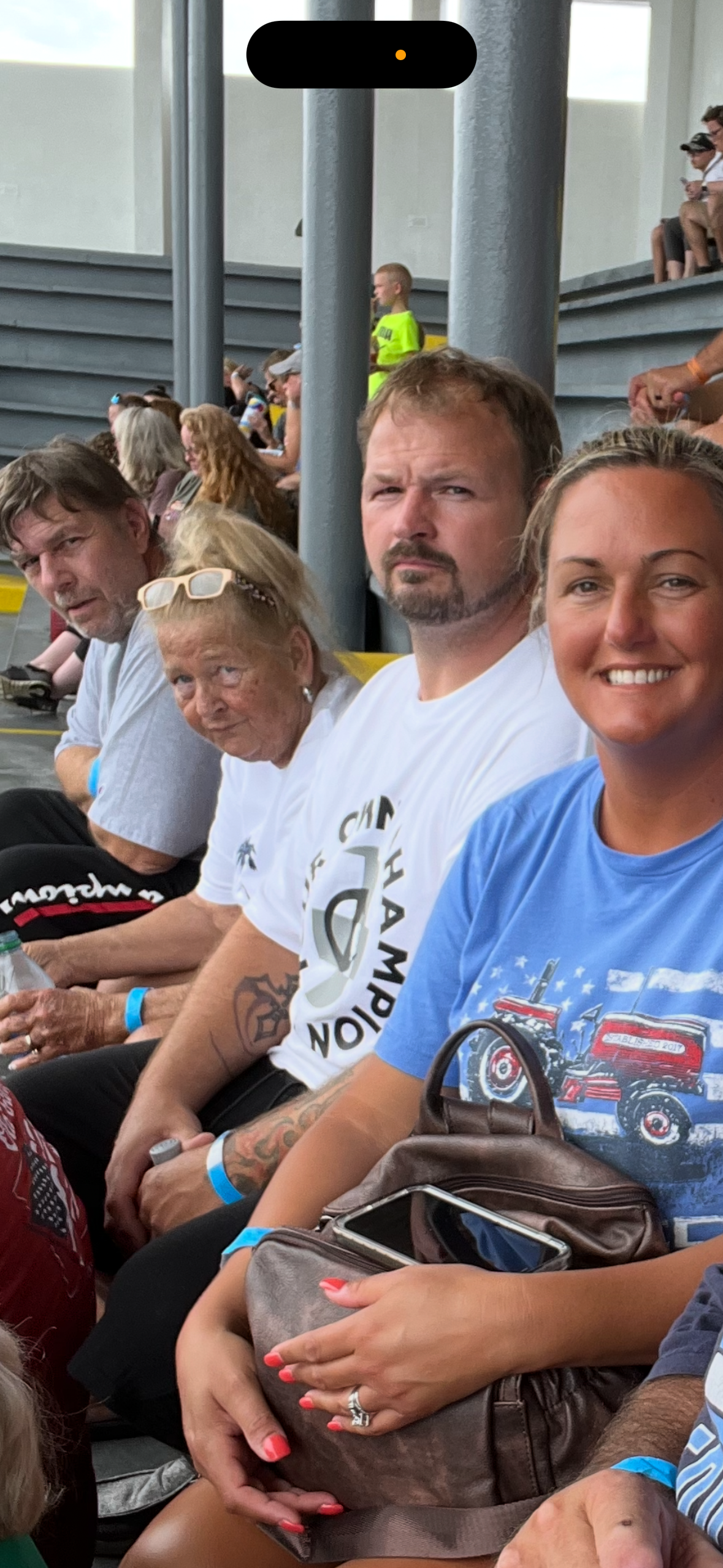 Spectators sit together, wearing casual clothing and expressing excitement, at a racetrack event.