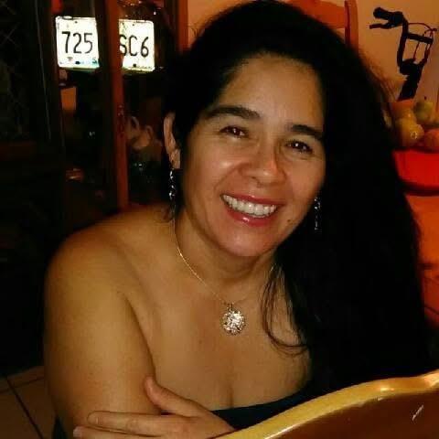 A woman sits at a table, smiling warmly while enjoying the lively atmosphere of the cafe.