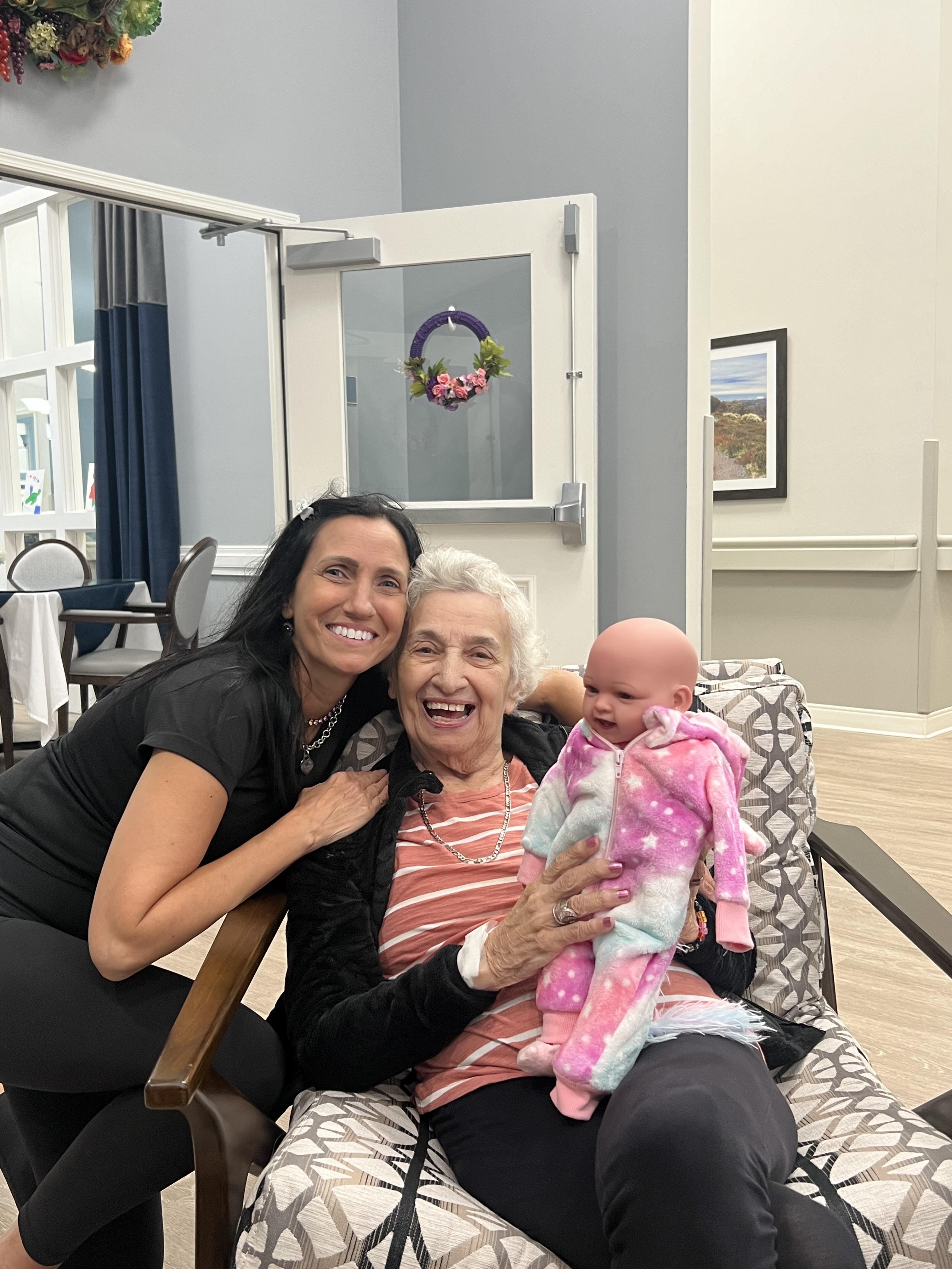 Two women joyfully pose with a baby, enjoying a moment of happiness in a welcoming space.