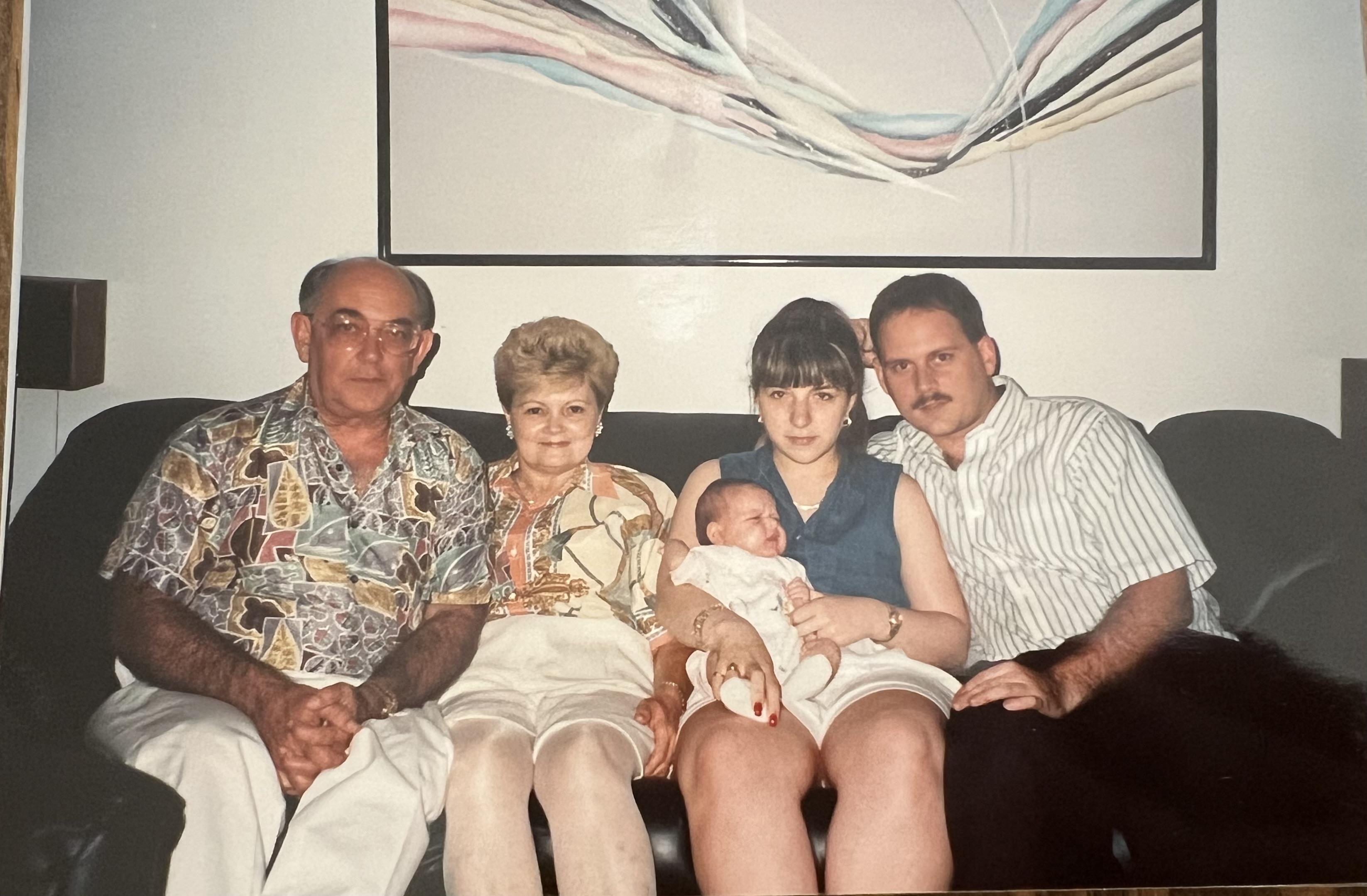 A family sits together on a couch, showcasing multiple generations and warm expressions.