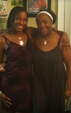 Two women stand side by side, smiling and enjoying their time together indoors.