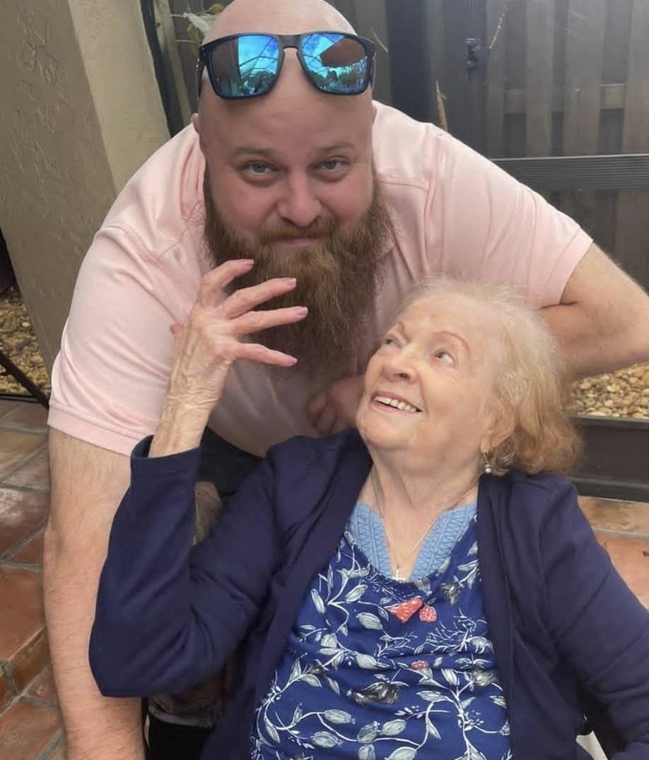 A man and an elderly woman enjoy a lighthearted moment outdoors, sharing smiles and laughter.