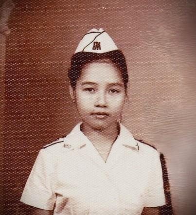 A young woman confidently wears a white uniform and hat, showcasing her professionalism.
