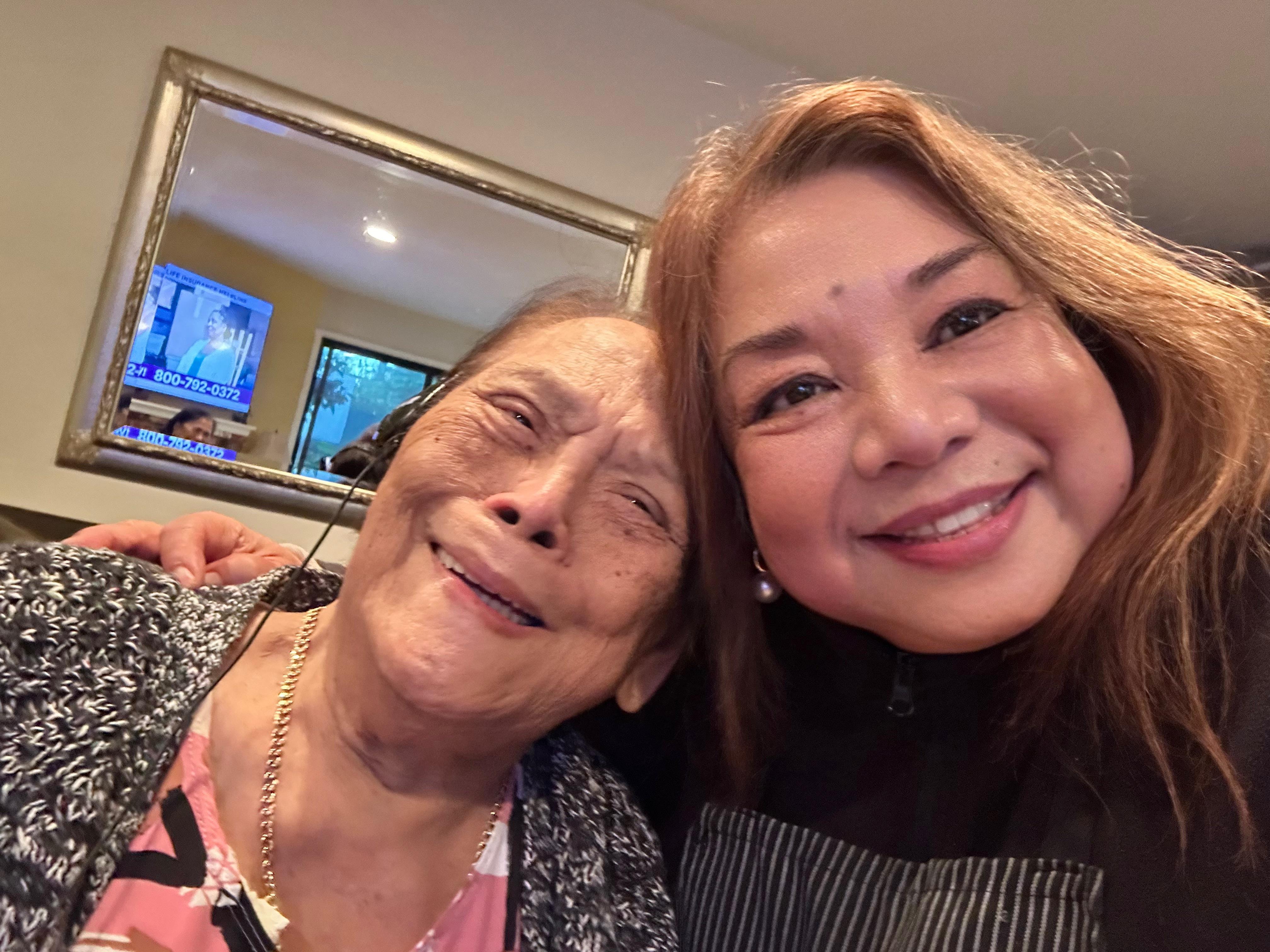 Two women share a joyful moment at home, smiling and embracing, showcasing their bond.