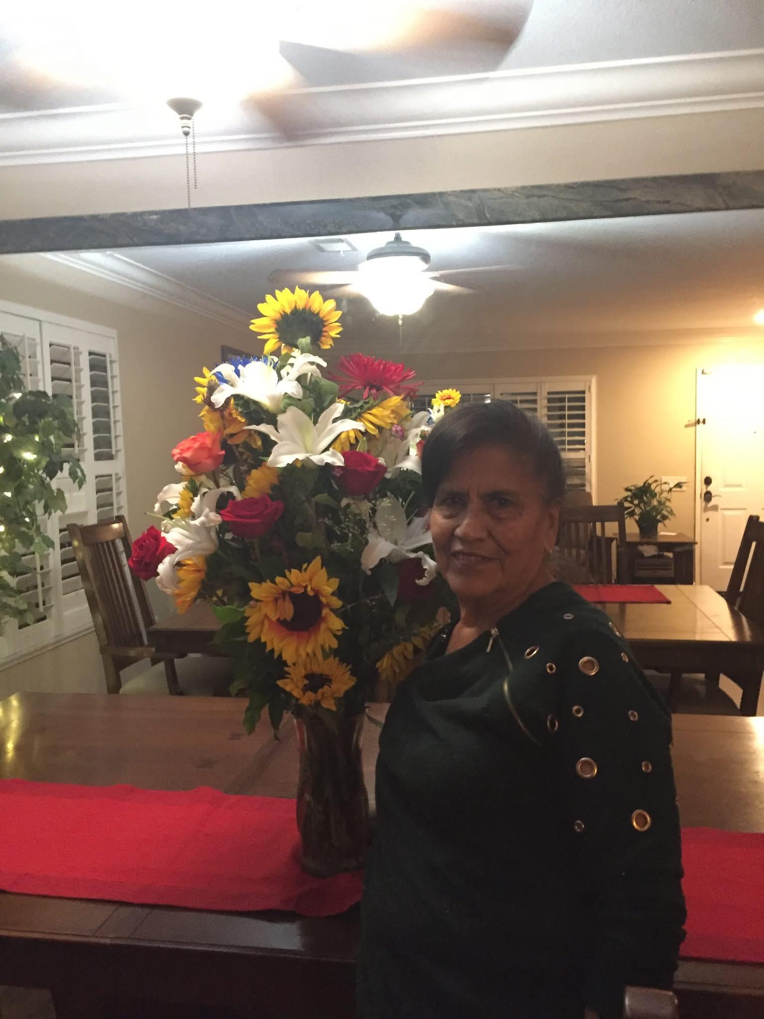 A woman stands proudly with a vibrant bouquet in a warmly lit dining space.