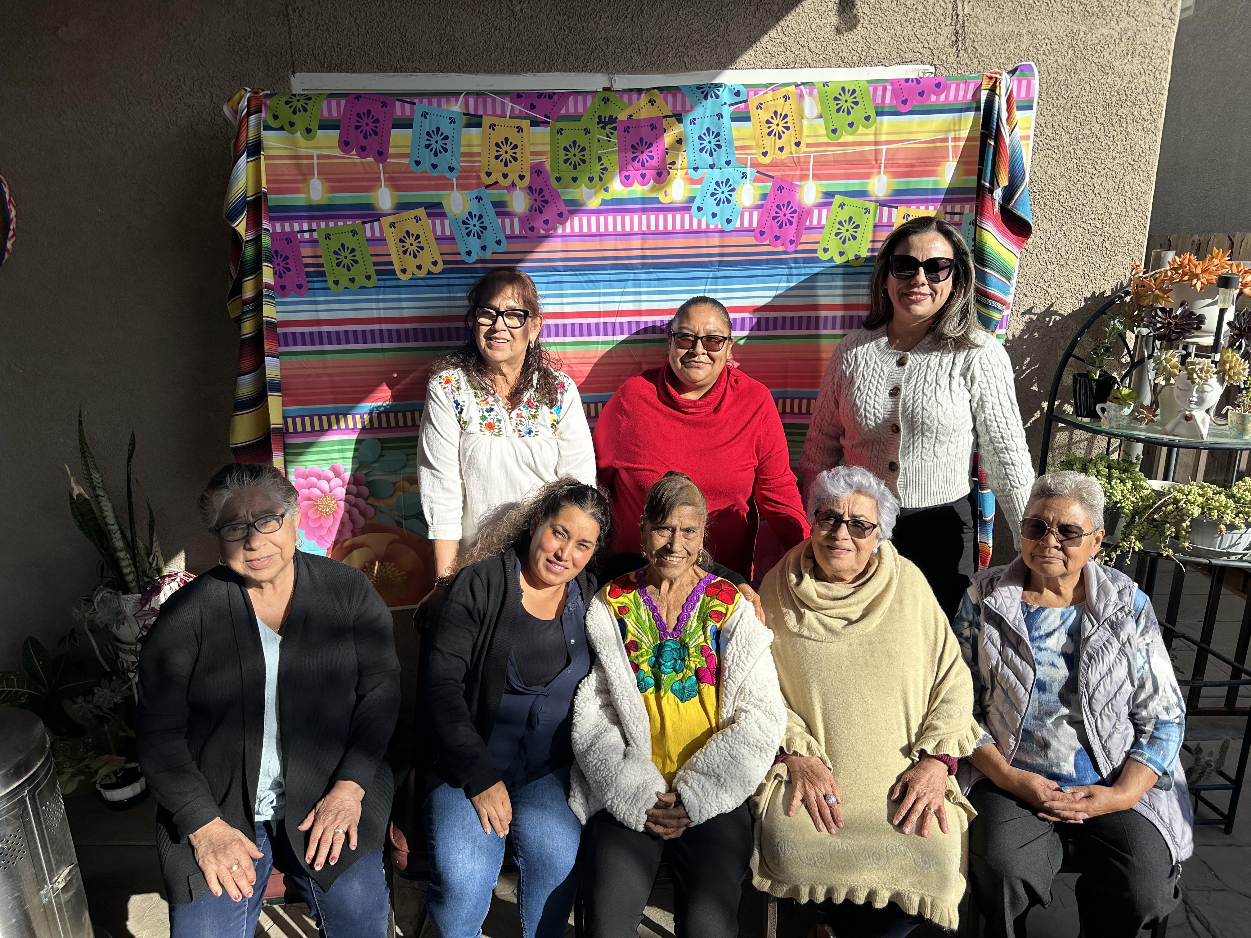 People gather joyfully, smiling and celebrating together in a vibrant outdoor setting.