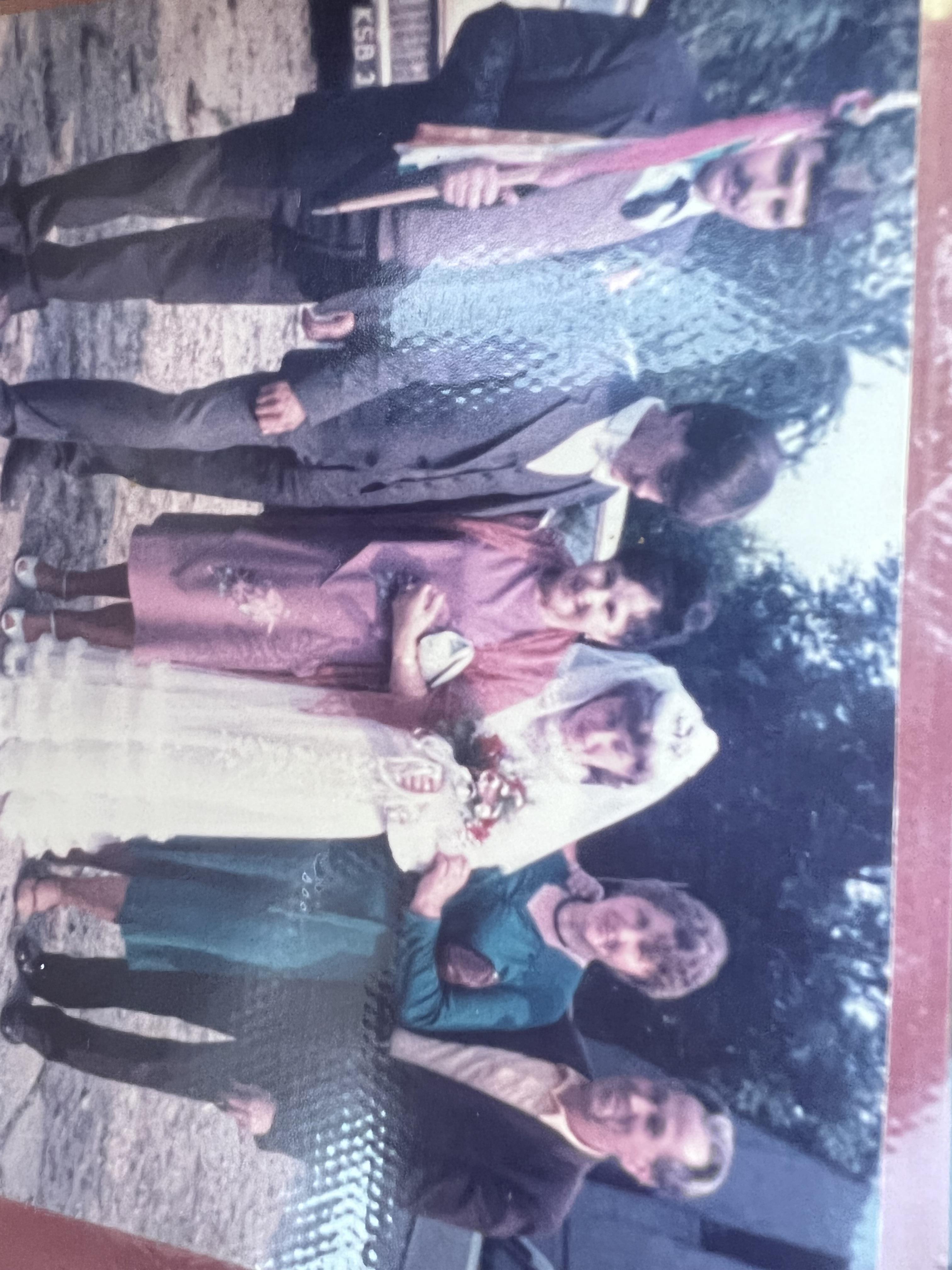 A family dressed in traditional clothing enjoys a cheerful gathering outdoors in a park.