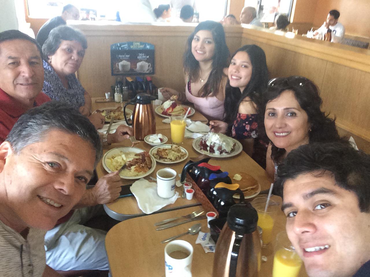 Group of friends gathered around a table sharing food and laughter during a brunch outing.
