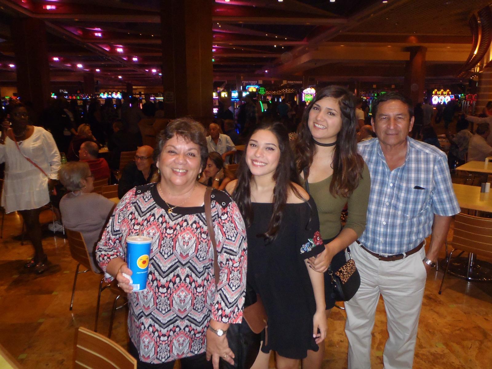 Four family members are gathered together smiling and posing in a vibrant, crowded location.