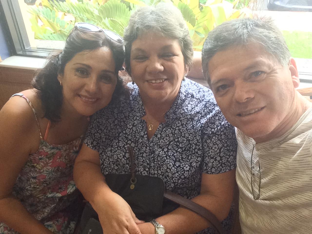 Three smiling individuals enjoy each other's company in a relaxed setting, sharing stories.