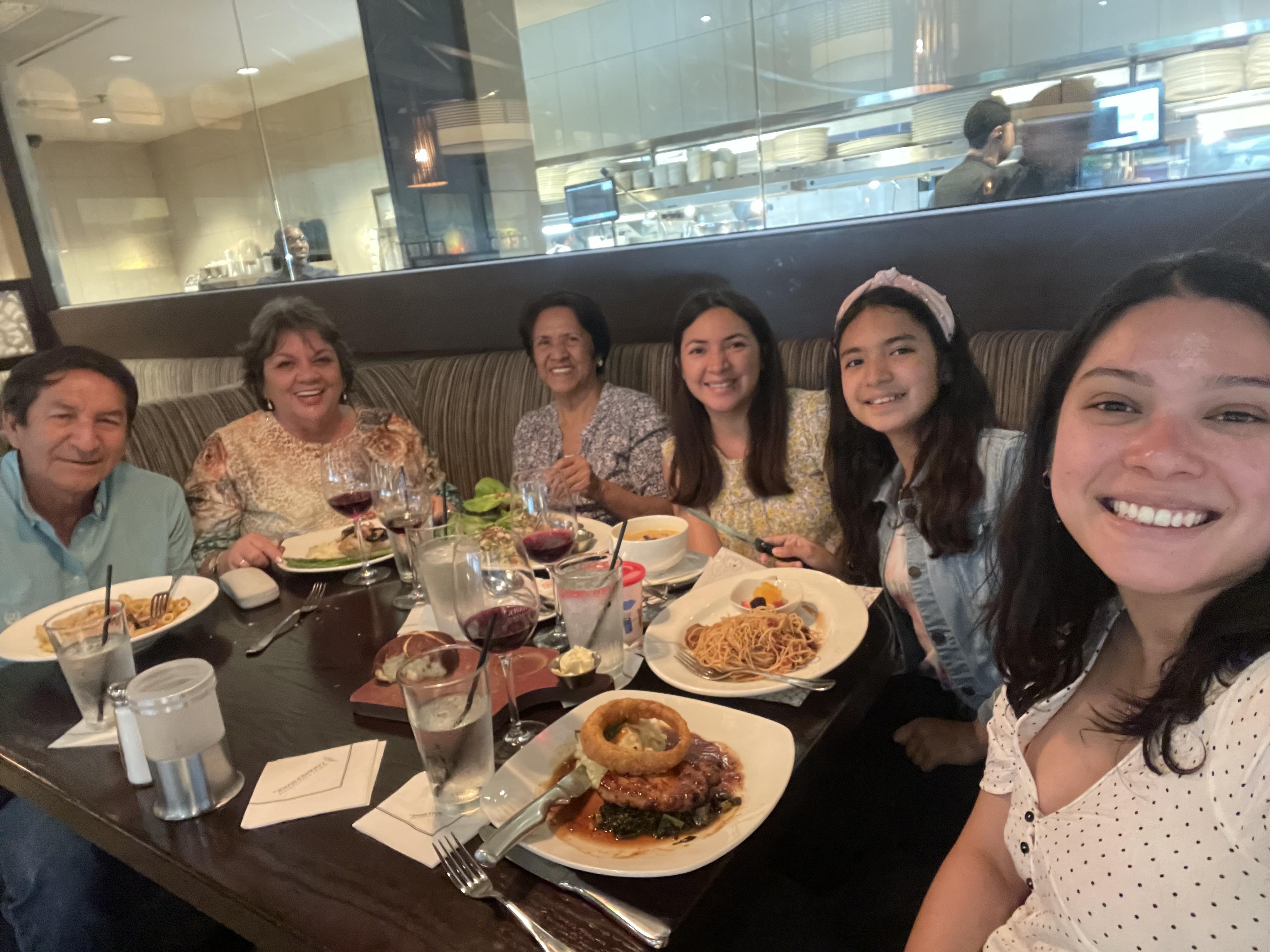 A group of friends share laughter and delicious food at a restaurant table while dining together.