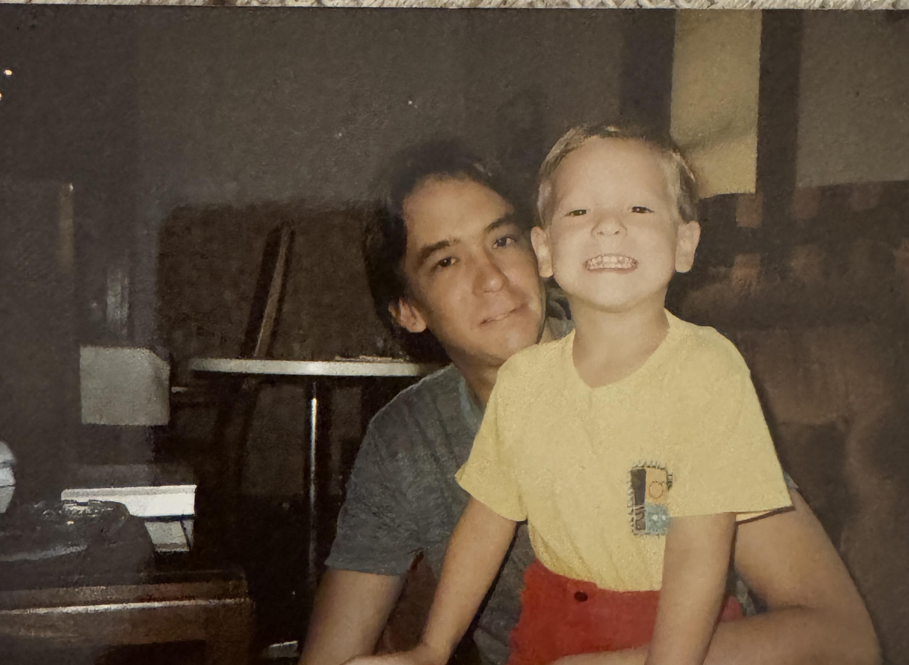 Child gleefully sits on an adult's lap in a warm, inviting home environment, showcasing joy.