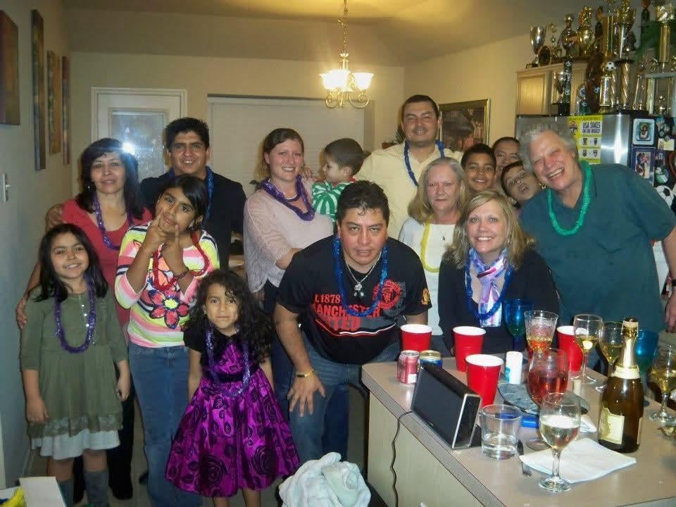 Friends and family gather indoors, smiling and enjoying each other's company during a celebration.