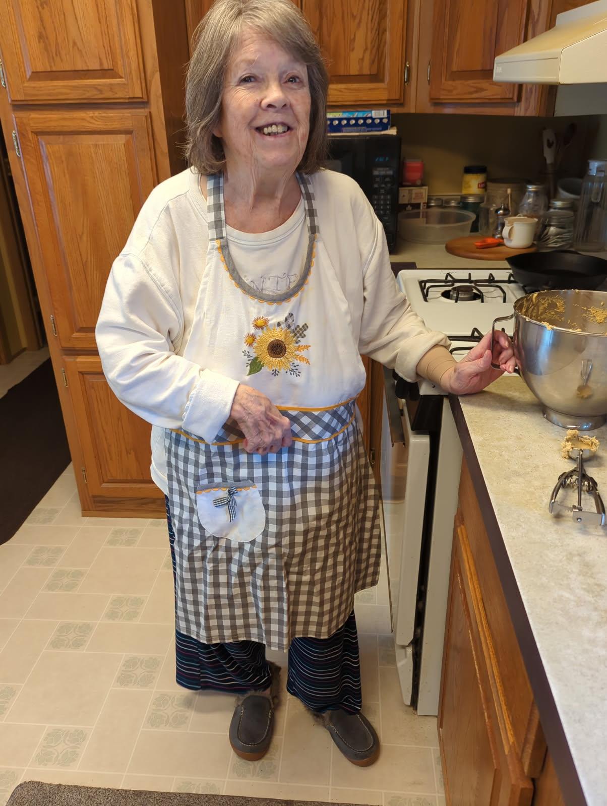 A cheerful chef stands in a warm kitchen holding a bowl while cooking with enthusiasm.