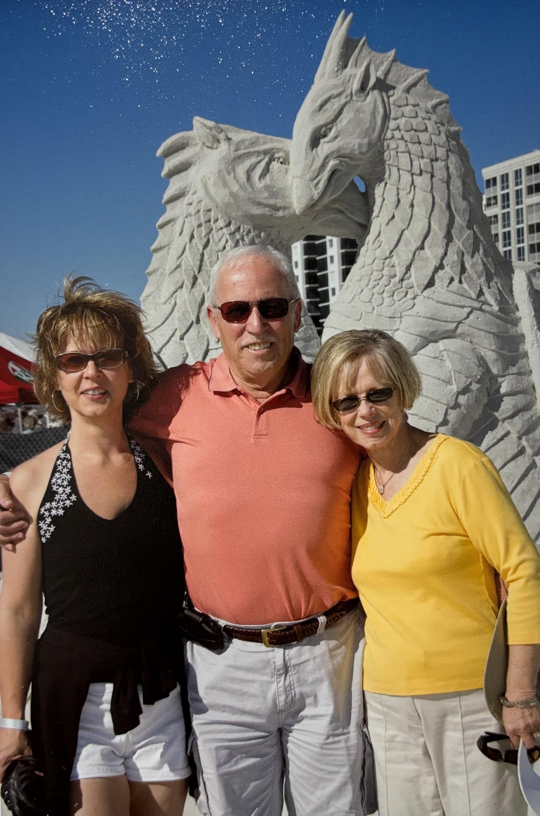 Friends stand in front of a dragon sculpture enjoying the festive atmosphere and sunshine.