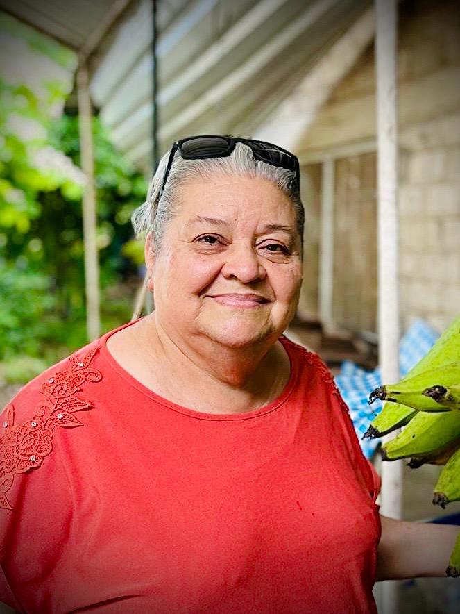 A joyful woman is enjoying her time in a vibrant market, showcasing fresh bananas.