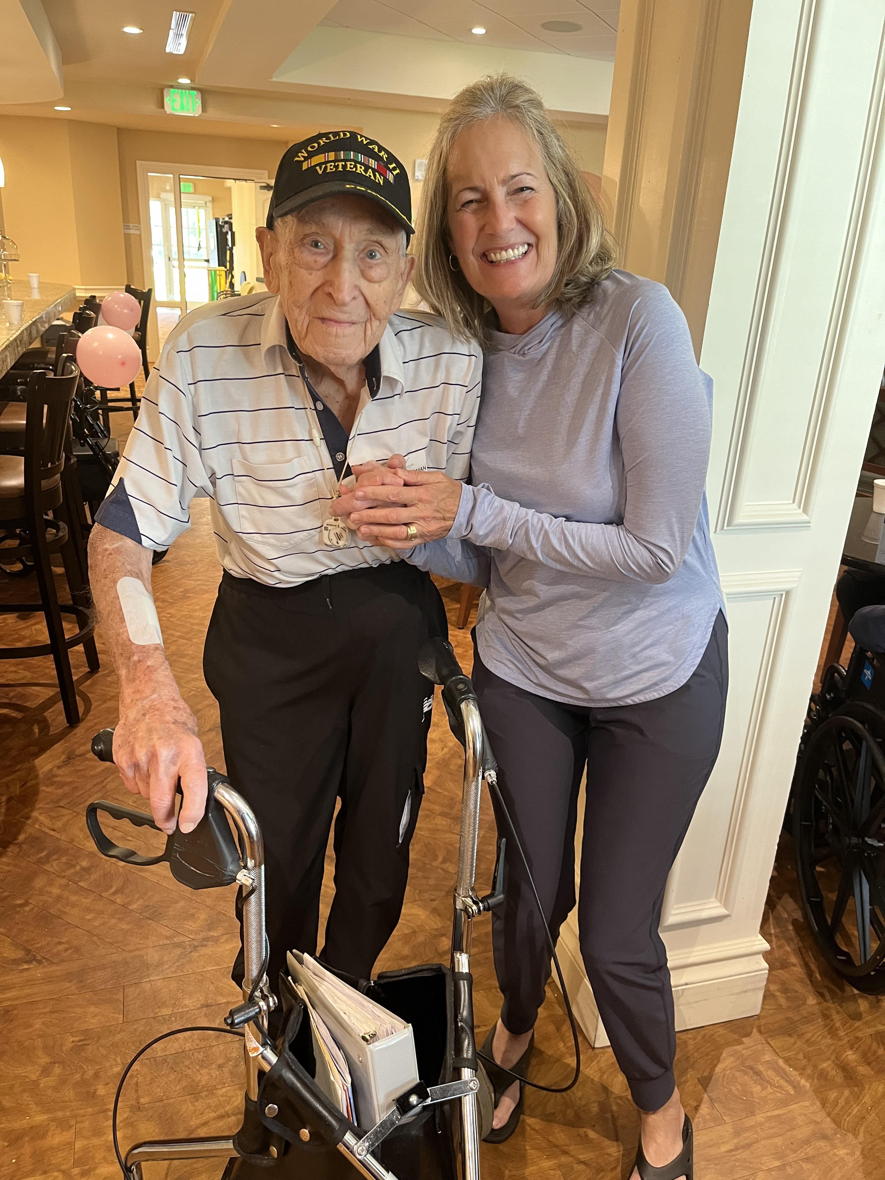 An elderly veteran and a woman share a joyful moment during a special gathering at a care home.