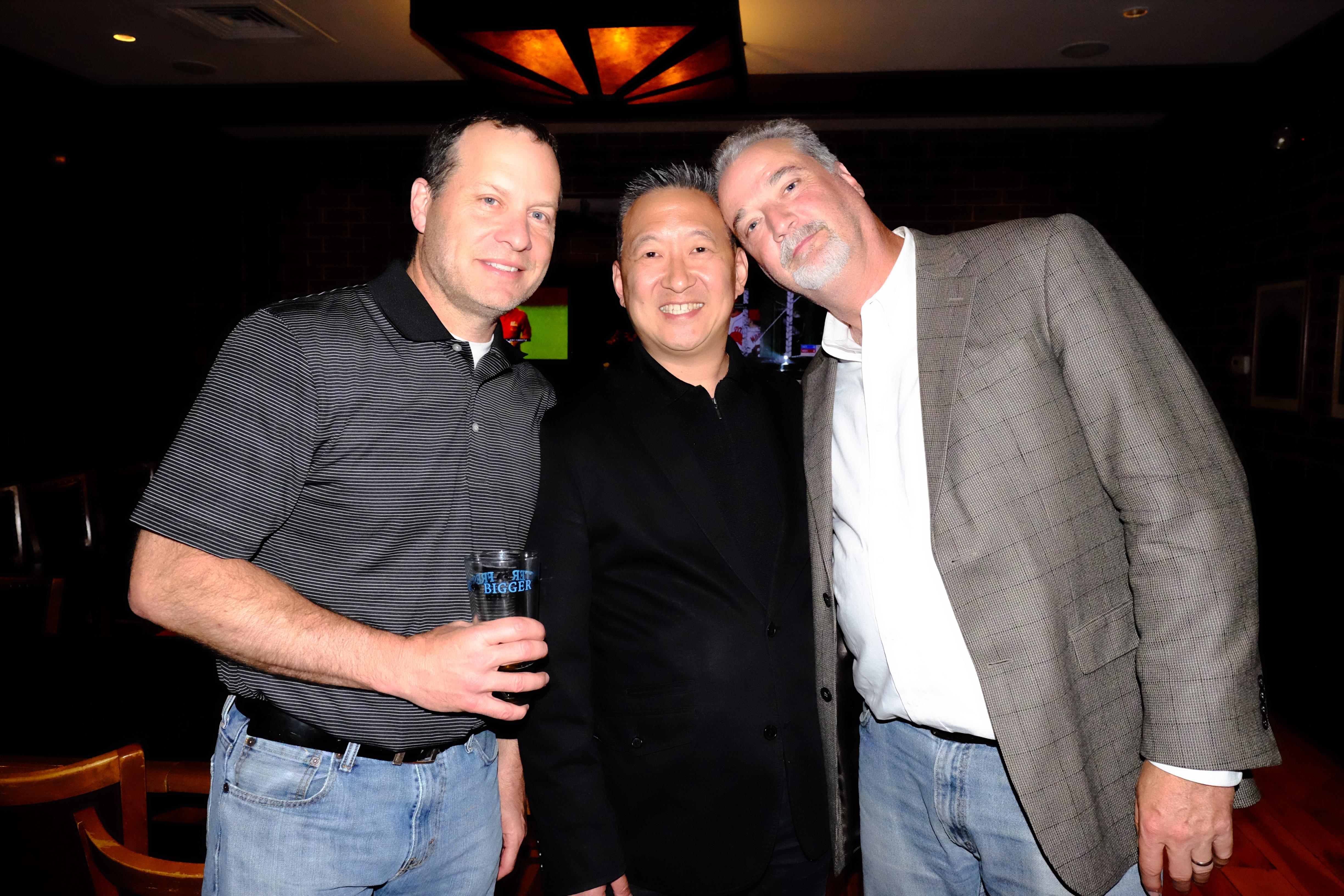 Three friends pose together at a lively venue during a fun night out, smiling happily.