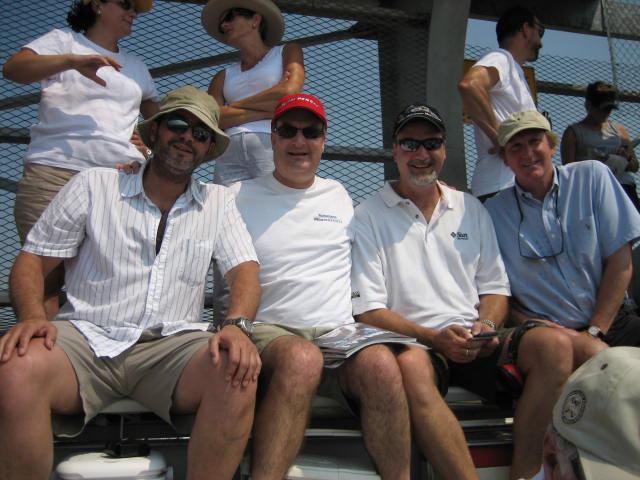 Four friends in casual wear enjoy a warm day at a sporting event.