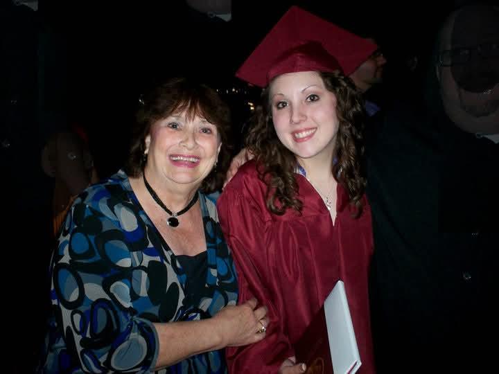 A joyful mother and daughter celebrate graduation together under dim lights at night.