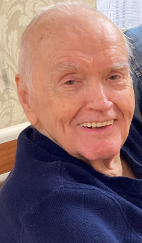 Elderly man with a cheerful smile relaxes at home, surrounded by family and positive energy.