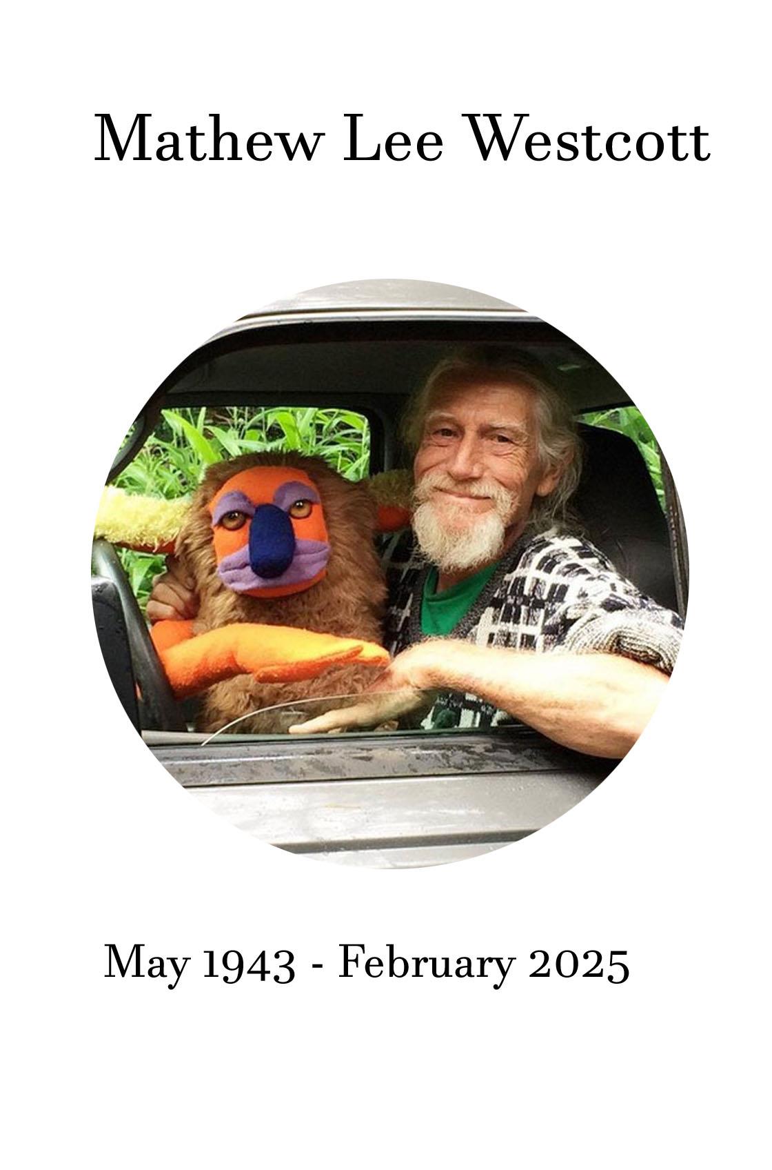 Mathew Lee Westcott enjoys a sunny day outdoors, smiling with a colorful plush toy.