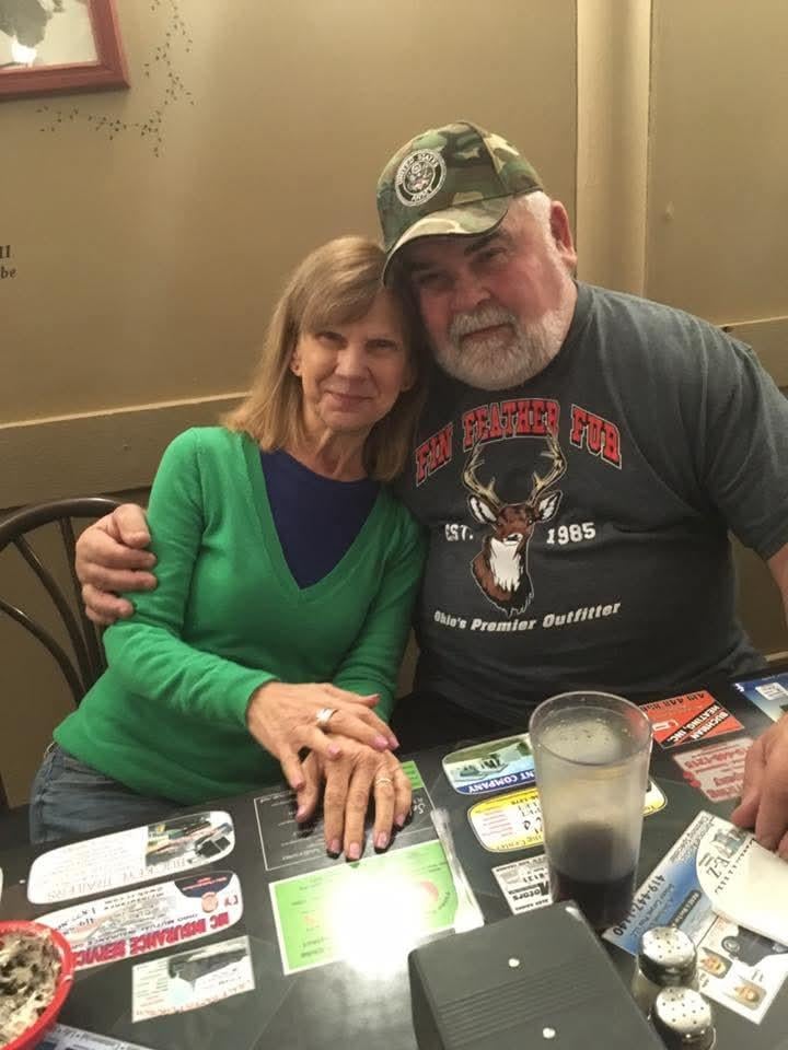 A man and woman are sitting together at a table, smiling and enjoying each other's company.