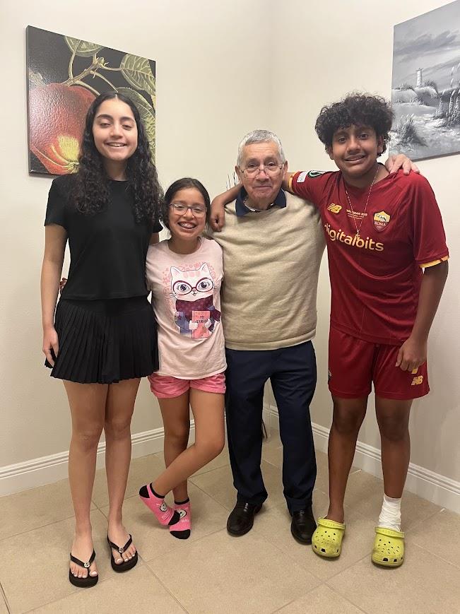 Children happily pose with their grandfather in a warm, inviting home environment.