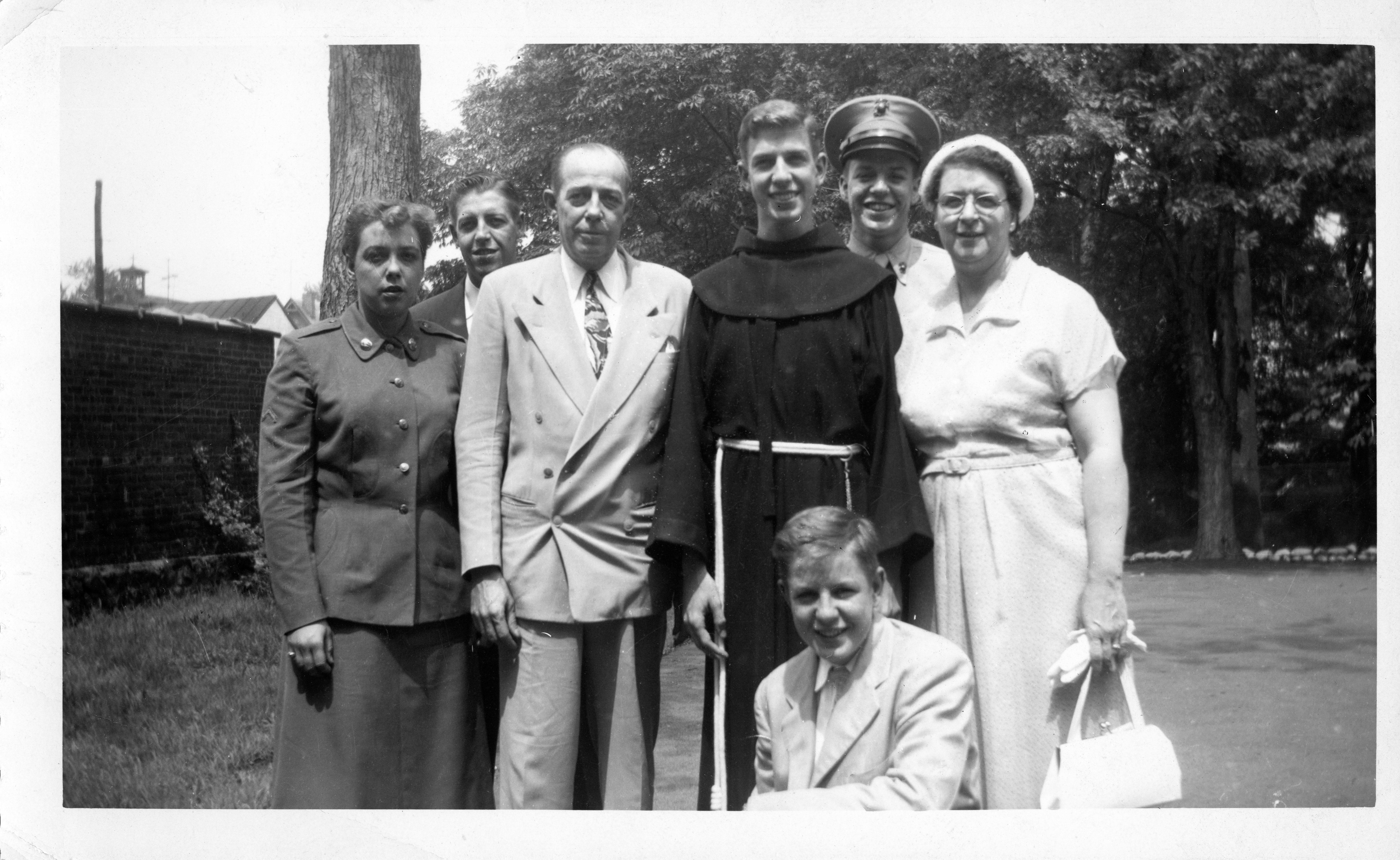 A family group stands together, showcasing joy and connection during a sunny day outdoors.